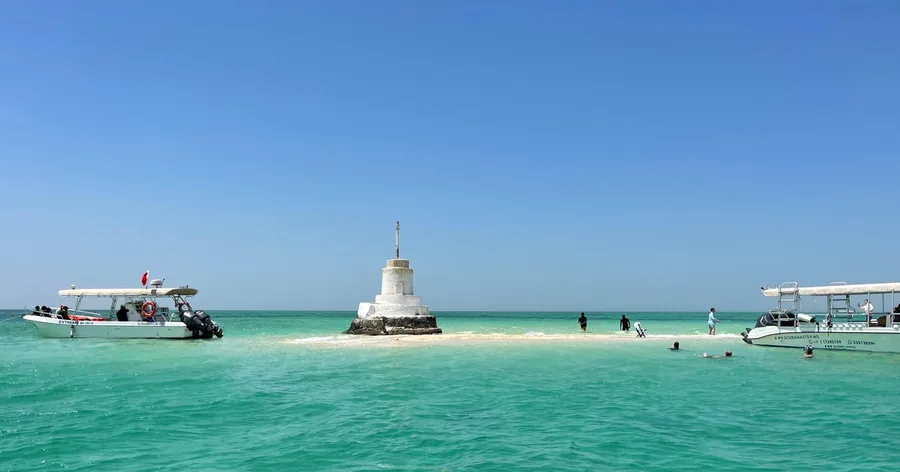 Türkisfarbenes flaches Wasser und eine helle Sandbank vor der Küste Bahrains, Boote in der Nähe