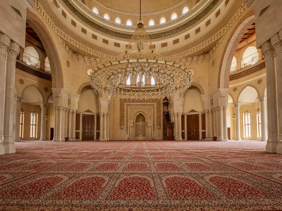 Der mit Teppichen ausgelegte Gebetssaal der Al-Fateh-Moschee unter der Kuppel, mit einem riesigen verzierten Kronleuchter und Marmorsäulen